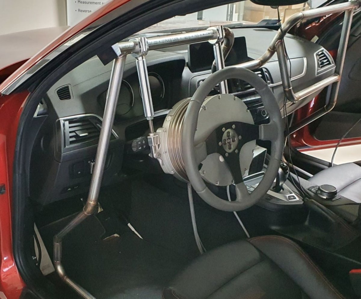 An existing steering robot held by a steel frame fixed in the footwell