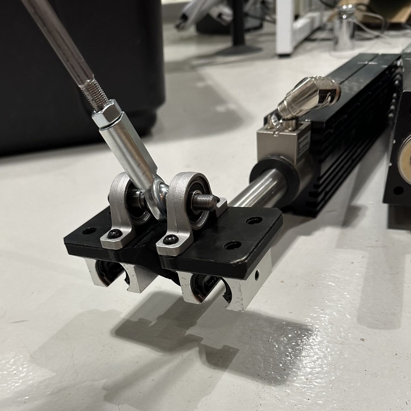 A slider carriage mounted on one of the lab's linear motors, with a link rising from its pivot
